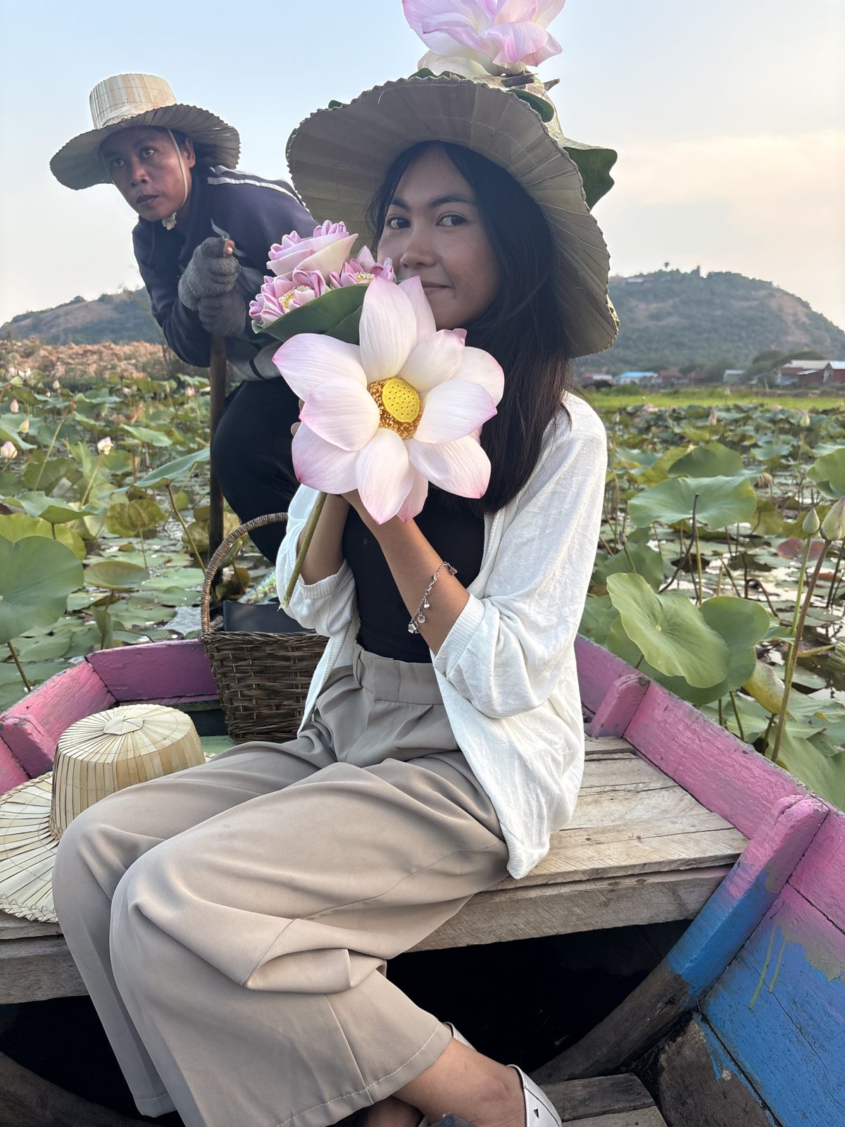A friend holding pink lotus flowers during a boat ride at the lotus farm